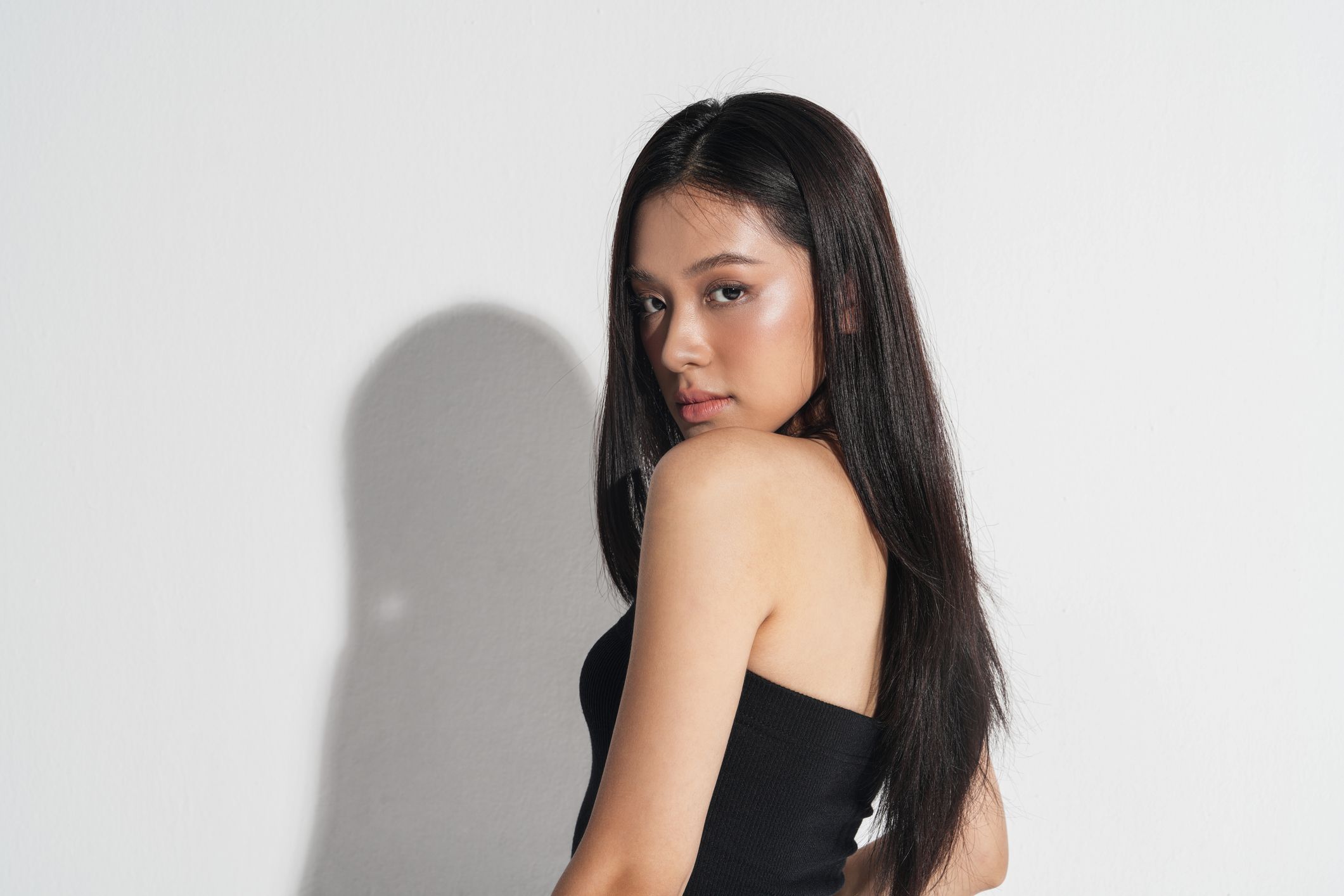 Model posing against a white background with shadow.